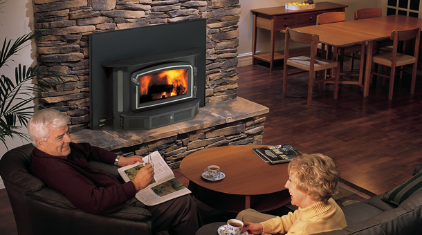 Couple comfortably sitting near a Regency Fireplace i3100 Wood Insert with Stone Surround and mantel